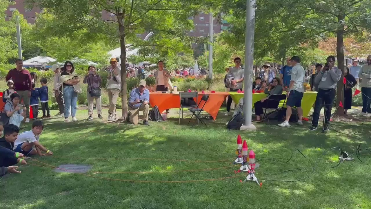 Load video: Three water rockets launching from a grassy lawn